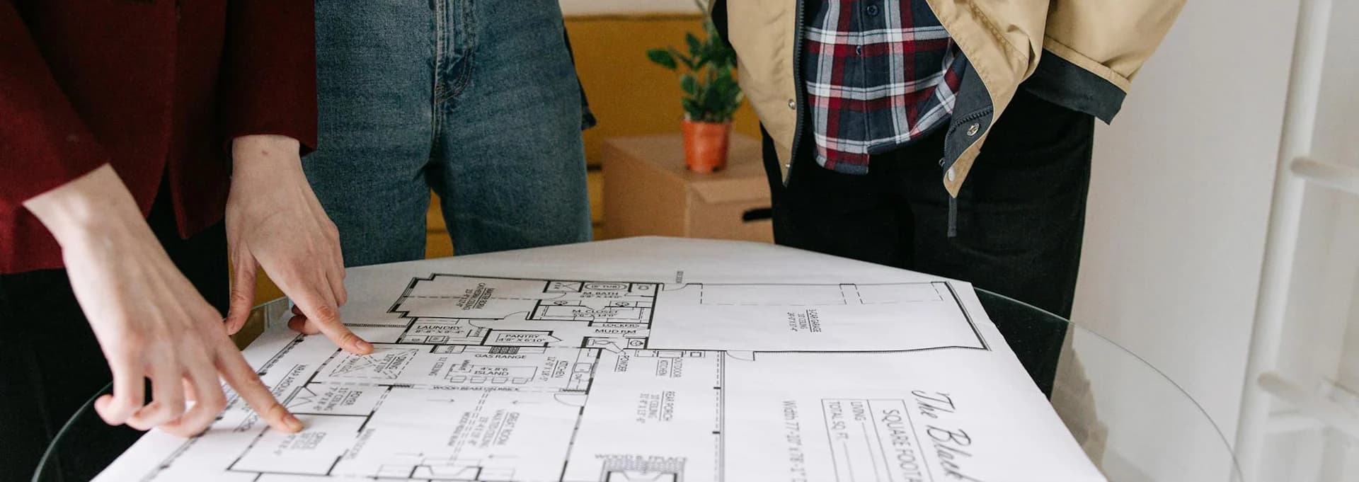 Hands pointing at architectural blueprints on table